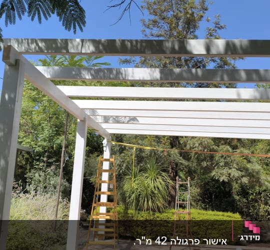 מבנה עץ לבן עם סולמות בגינה ירוקה.